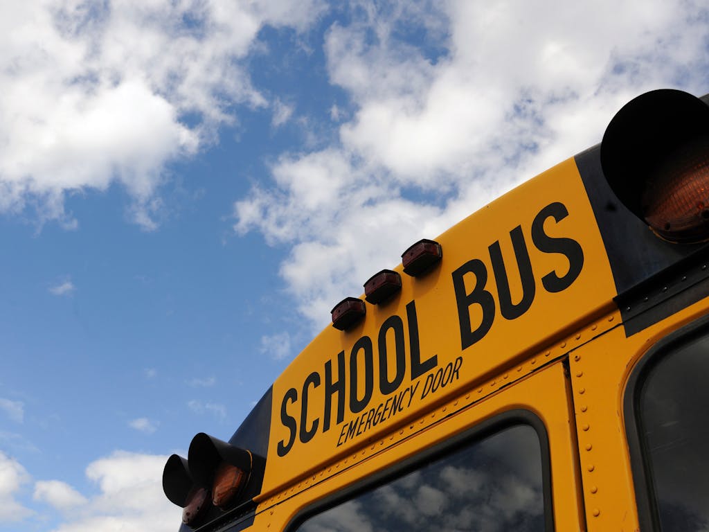 School Avoidance: How We Help Kids Get Back to School 1 Close-up shot of a yellow school bus with a blue sky background, showcasing cloud formations.
