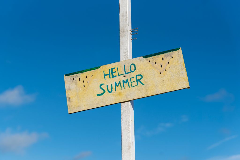 A cheerful 'Hello Summer' sign against a bright blue sky, symbolizing the joyous arrival of summer, the perfect time for summer threapy.