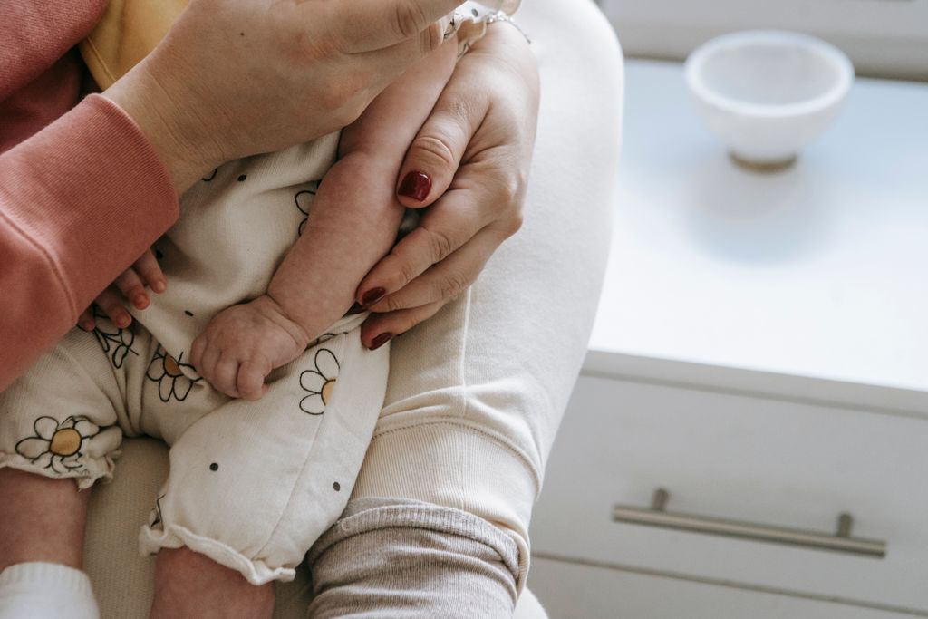 Perinatal Mental Health Therapy 1 Crop unrecognizable mother in casual clothes embracing baby in arms while sitting in light room